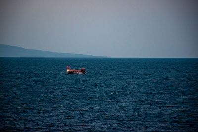 Boat sailing in sea against clear sky