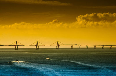 Bridge over sea against sky during sunset