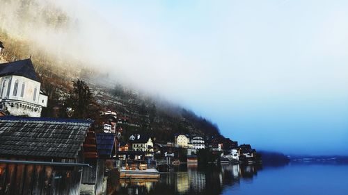 Buildings by lake against sky