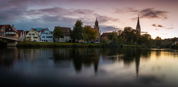 Reflection of trees and buildings in lake against sky