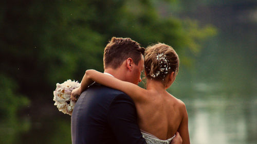 Bride and bridegroom standing by lake