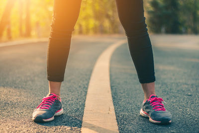 Low section of woman wearing sports shoes while standing on road