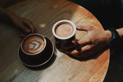 Couple holding coffee cup on table