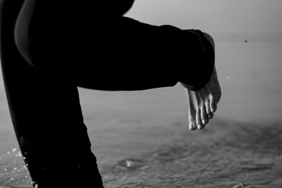 Low section of man standing on sand at beach