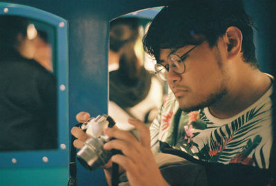 Portrait of young man holding camera in car