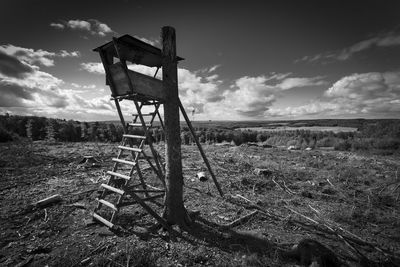 Old chair on field against sky