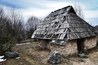 House amidst trees and rocks against sky