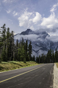 Road by trees and mountains against sky