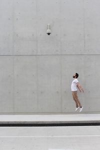 Full length of young man walking on concrete wall
