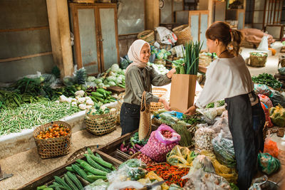 Rear view of woman with vegetables for sale at market