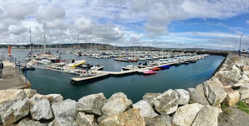 Sailboats moored in harbor against sky