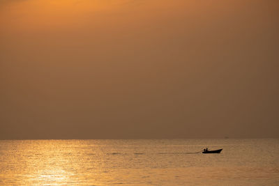 Silhouette boat in sea against sky during sunset