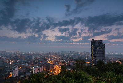 Illuminated buildings in city against sky during sunset