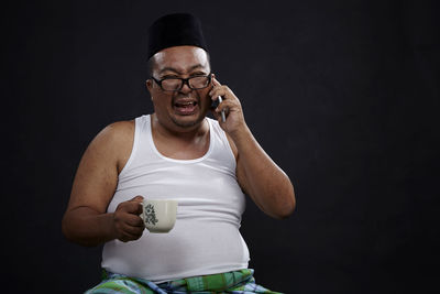 Man holding smart phone while standing against black background