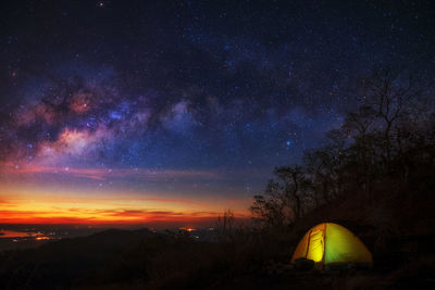 Illuminated tent on field against star field at night