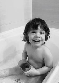 Happy boy holding toy in bathtub