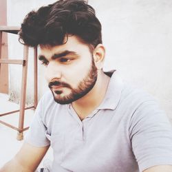 Close-up of thoughtful man with beard against wall