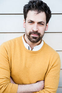 Portrait of young man standing against wall