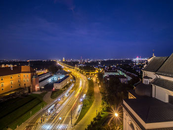 High angle view of illuminated street amidst buildings in city at night