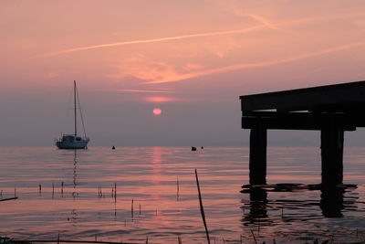 Silhouette sailboat on sea against sky during sunset