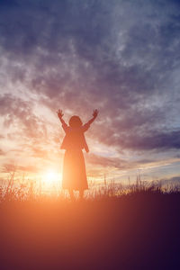 Silhouette person standing on field against sky during sunset