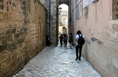 People walking on footpath amidst buildings in city