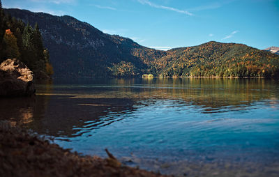 Scenic view of lake and mountains against blue sky