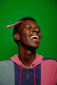 Smiling man with comb in hair against green background