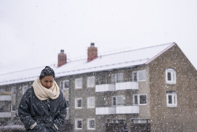 Portrait of woman on snow against building