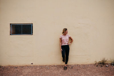 Full length of woman standing against wall