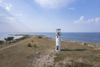 Lighthouse by sea against sky