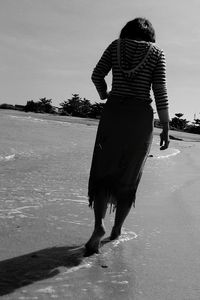 Rear view of woman walking on beach