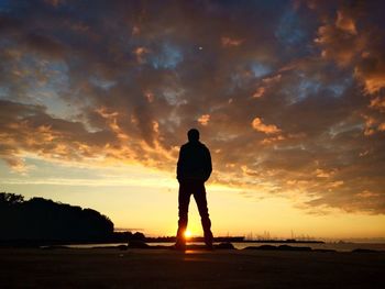 Silhouette man standing on beach against sky during sunset