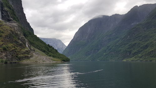 Scenic view of river and mountains at naeroyfjord against cloudy sky