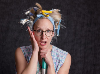 Portrait of woman wearing hair curlers against wall