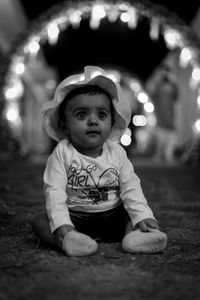 Portrait of cute baby girl sitting at night