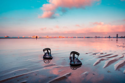 Sandals on the beach against sky during sunrise