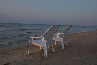 Empty chair on beach against clear sky