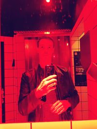 Man photographing with mobile phone in illuminated building