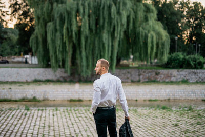 Rear view of young man looking away while standing outdoors