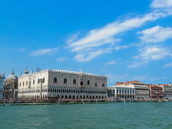 View of buildings at waterfront against cloudy sky
