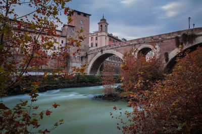 Arch bridge over canal amidst buildings against sky