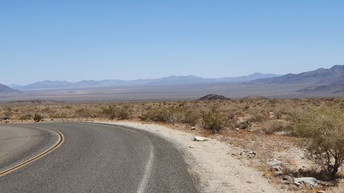 Road by desert against clear sky