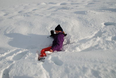 High angle view of teenage girl sitting on snow covered field