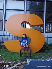 Portrait of boy sitting on built structure