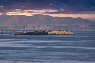 Scenic view of sea and mountains against sky during sunset