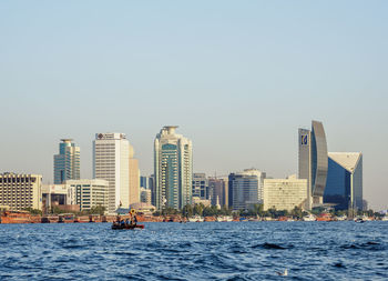 Sea by buildings against clear sky