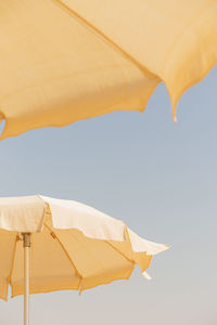 Two beige cotton beach umbrellas against a blue sky. abstract background from summer travel