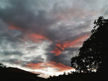 Low angle view of silhouette trees against dramatic sky