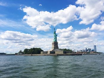 Statue in city against cloudy sky